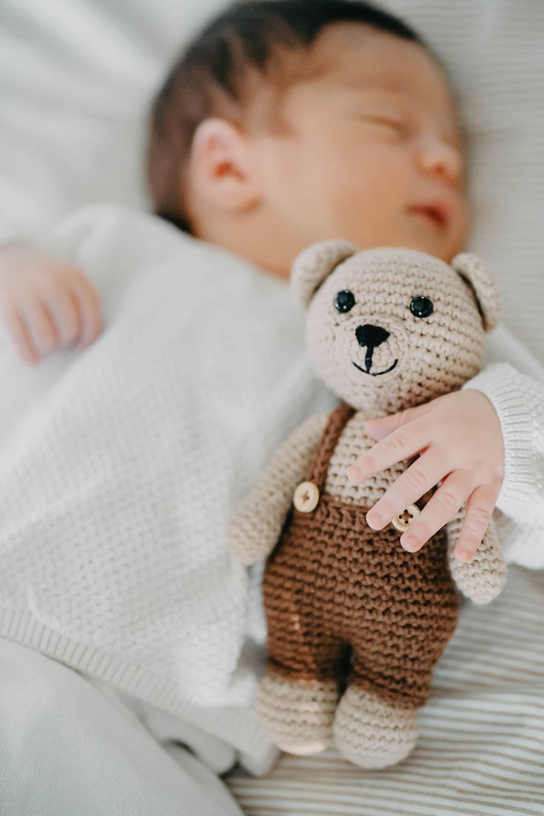 Sleeping newborn baby with a knitted teddy bear