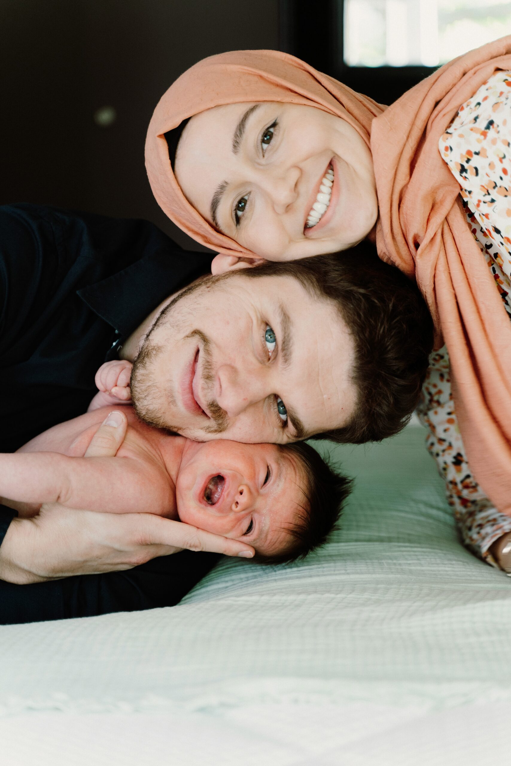Parents smiling close together with their baby