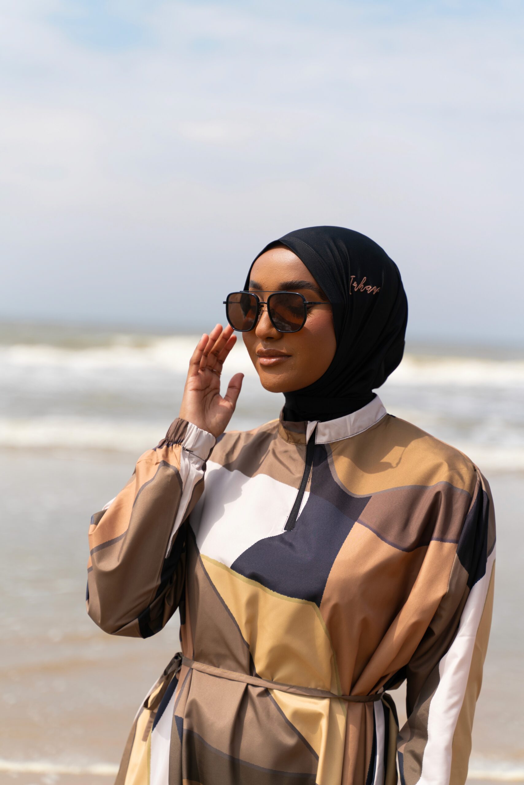 Woman in sunglasses and a black headscarf on the beach