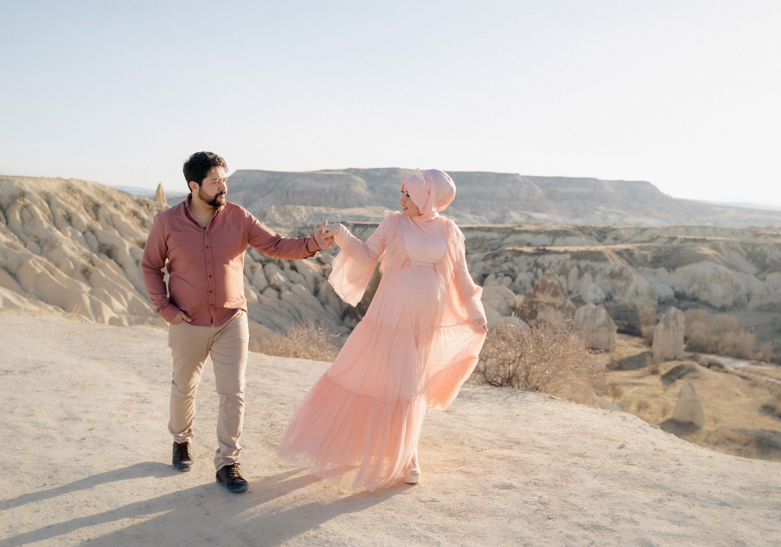 Couple holding hands on a hillside in Cappadocia at golden hour