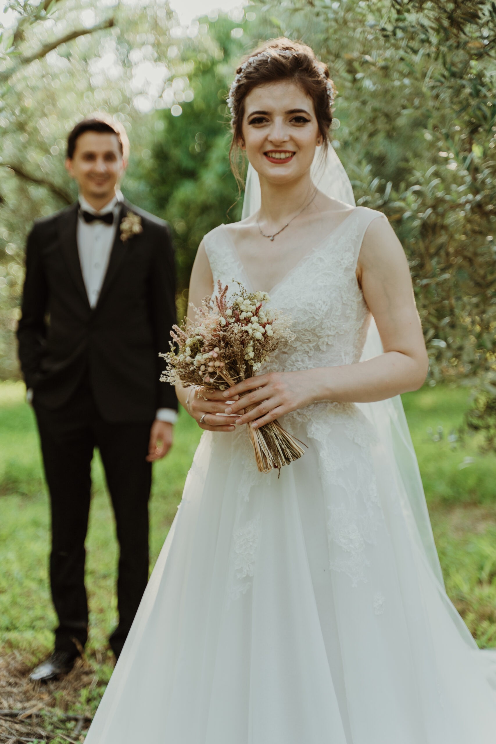 Bride and groom standing among green trees
