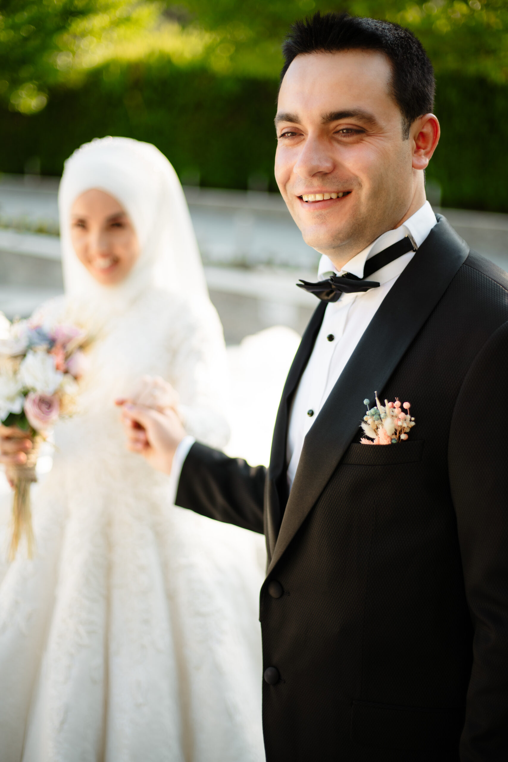 Smiling bride in a white hijab and groom in a tuxedo