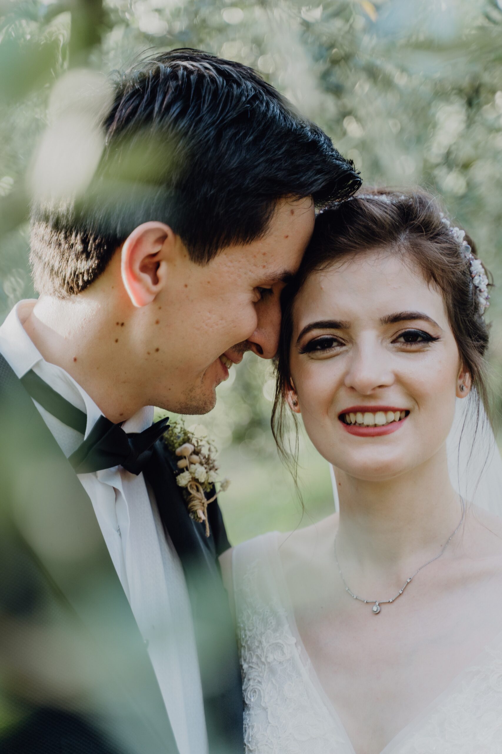 Close-up of a smiling bride and groom, foreheads touching