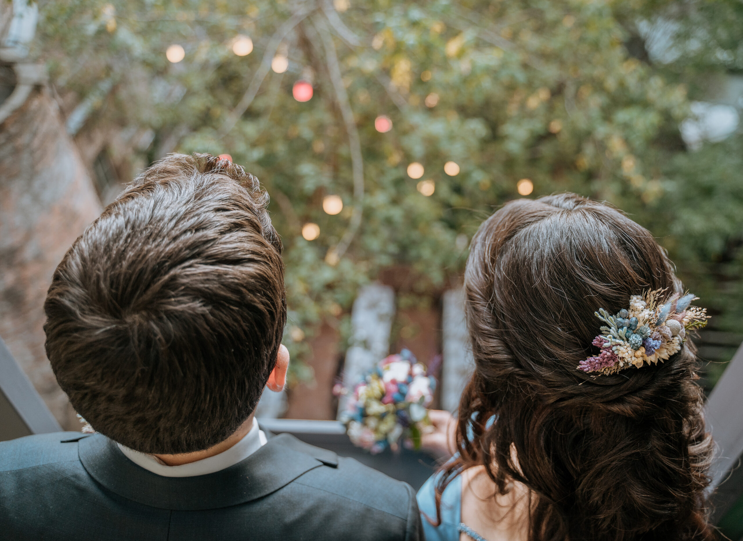Couple seen from behind watching string lights at their wedding