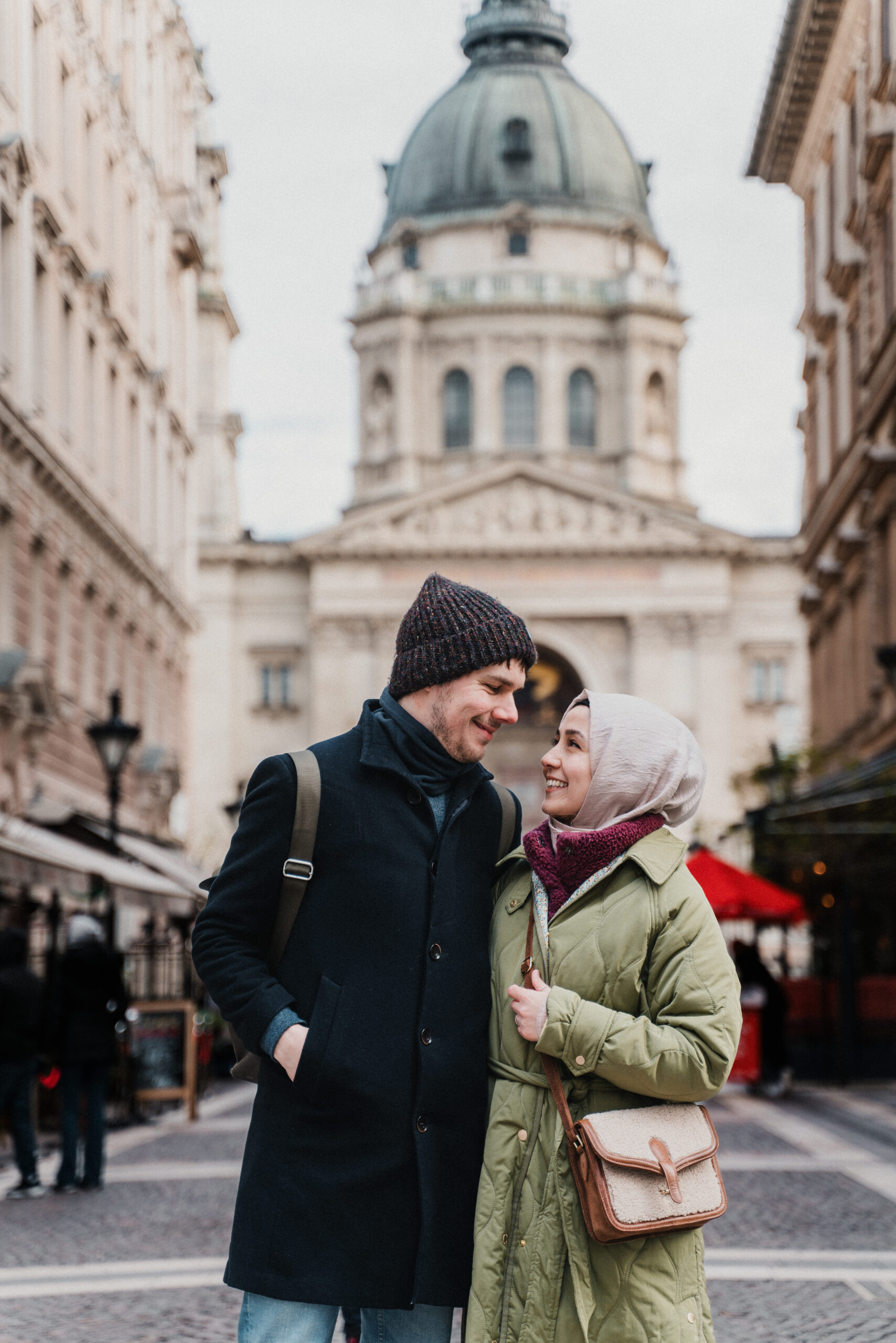 Couple embracing on a city street with a domed building behind them