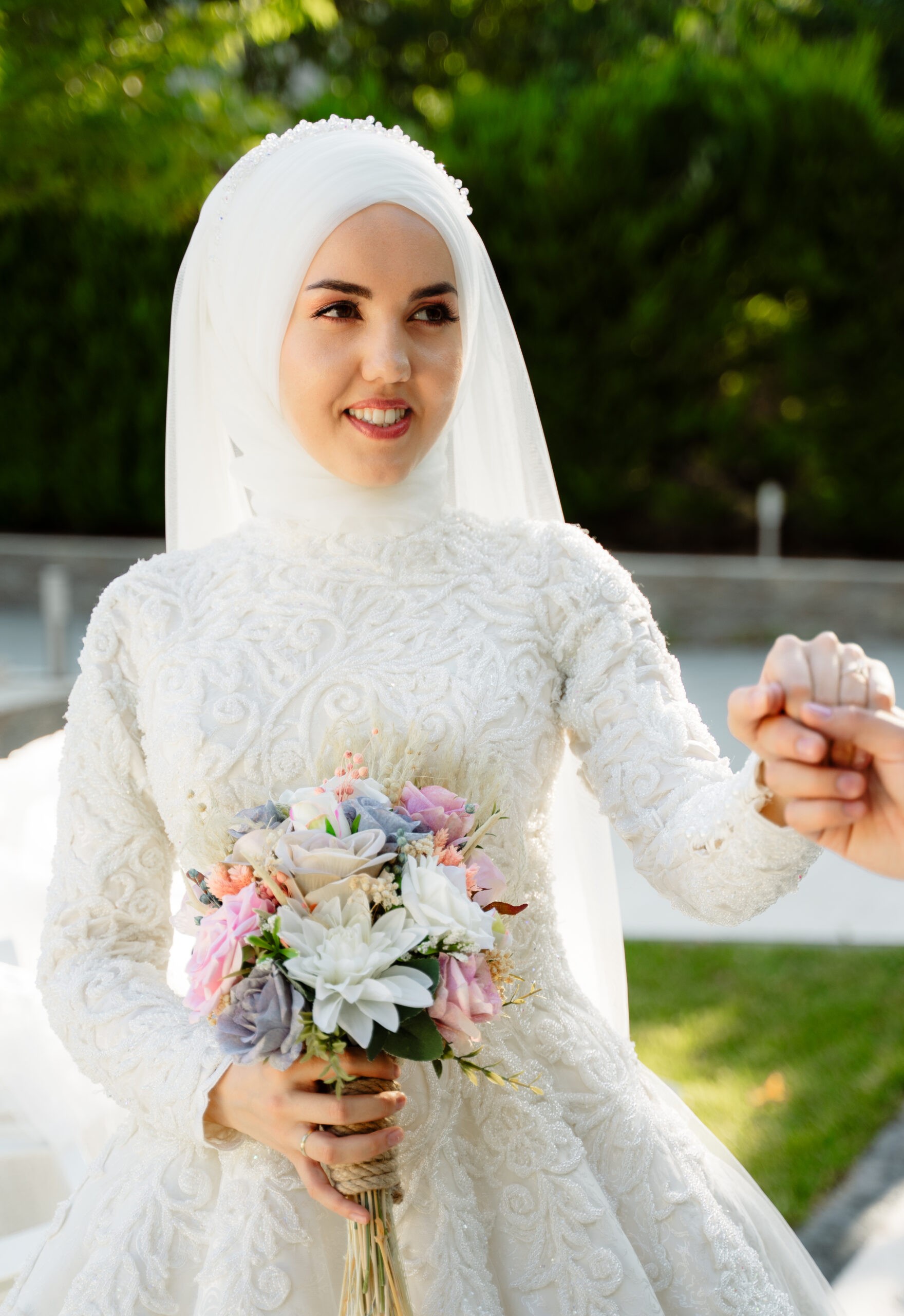 Bride in a white hijab and lace gown holding her bouquet
