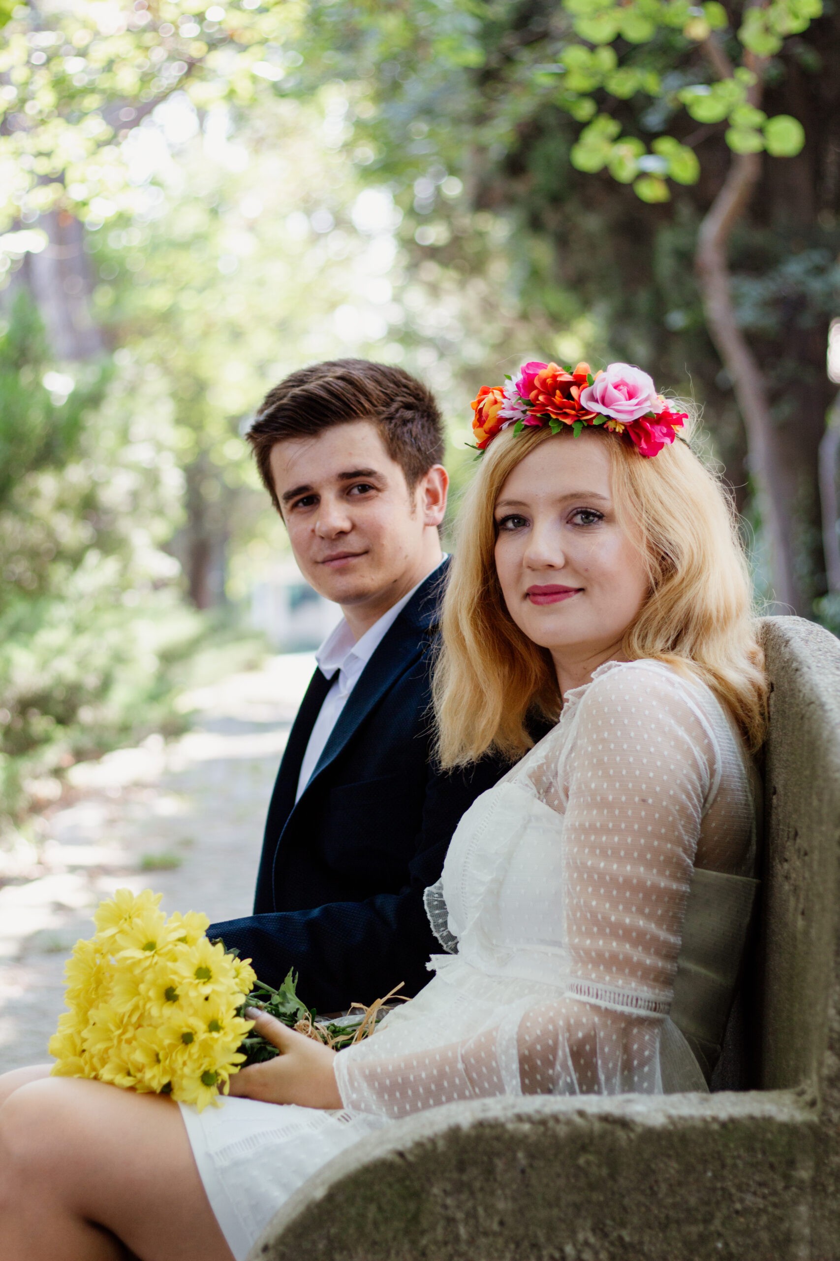 Couple sitting together outdoors, the woman wearing a flower crown